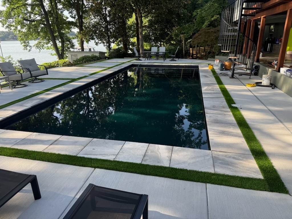 Finished renovation — dark-bottom pool with turf ribbons and lake view